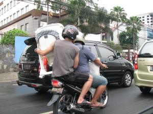Carrying a baby carrier on a motorcycle, the vehicle of choice for millions in Jakarta